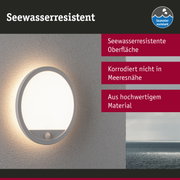 Runde weiße Wandlampe mit seewasserresistenter Oberfläche und warmem Licht an grauer Wand