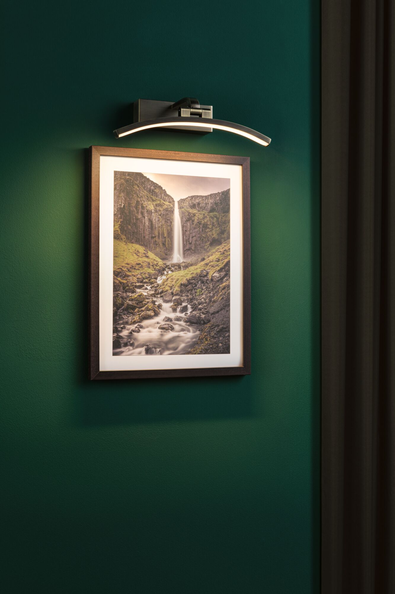 Moderne LED-lichtarmatuur van geborsteld metaal met warm wit licht op groene wanddecoratie.