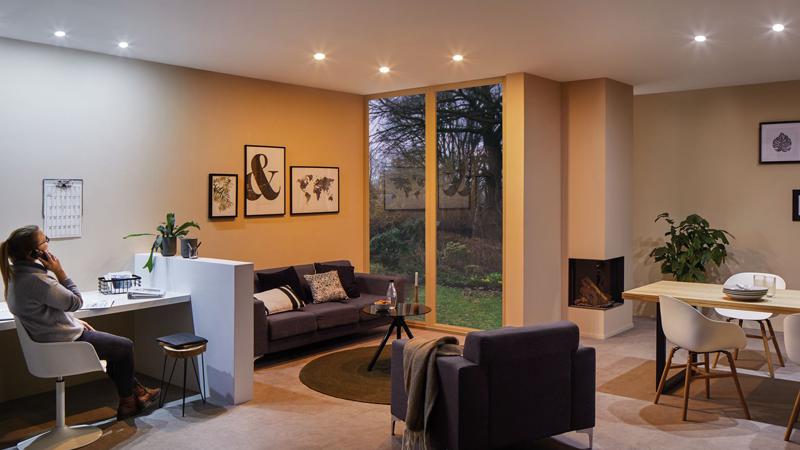 Salon moderne avec spots encastrés blanc chaud, canapé et grande fenêtre, éclairage d'ambiance confortable