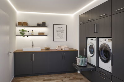 Modern laundry room with LED ceiling and shelf lighting, grey cabinets and wooden countertop