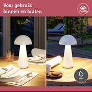 Witte tafellamp met IP44 bescherming voor binnen- en buitengebruik op houten tafel met servies.