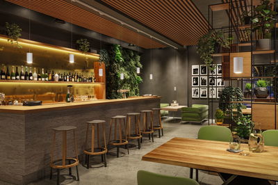 Modernes Barinterieur mit Holztheke, grünen Sitzmöbeln und weißen Pendelleuchten für Gastronomiebeleuchtung.