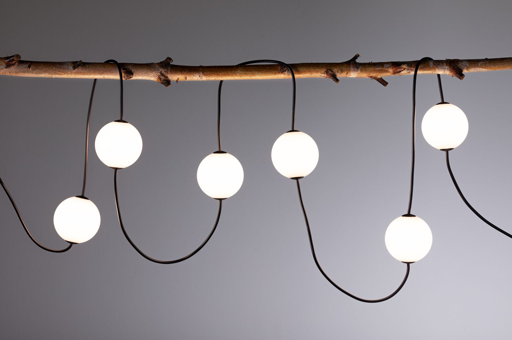 Moderne LED-Lichterkette mit weißen Kugeln an braunem Holzstab für stimmungsvolle Beleuchtung
