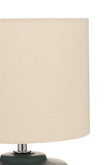 Table lamp with cream fabric shade and dark green base for cozy ambient lighting
