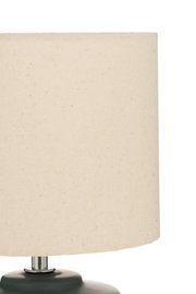 Table lamp with cream fabric shade and dark green base for cozy ambient lighting