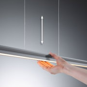 Hand holding grey LED pendant light with warm white illumination and adjustable height for interiors