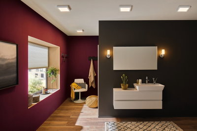 Salle de bain moderne avec appliques murales blanches et meuble lavabo sur mur noir, sol en bois et mur d'accent rouge
