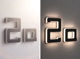 Modern house number 2a in black material with white LED lighting on wall shown day and night