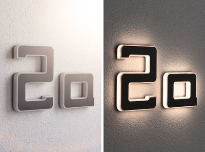 Moderne Hausnummer 2a aus schwarzem Material mit weißer LED-Beleuchtung an Wand bei Tag und Nacht