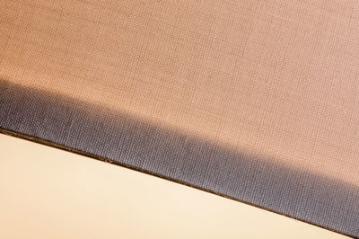 Close-up van beige stof met grijze rand, geschikt voor lampenkappen en verlichtingsaccessoires.