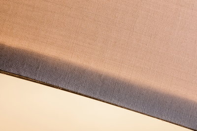 Gros plan sur tissu beige avec bord gris, adapté aux abat-jours et accessoires d'éclairage.