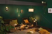 Living room with green wall, brown pallet chairs and various modern glass and metal pendant lights