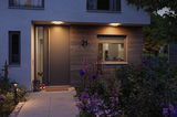 Porte d'entrée moderne avec bardage en bois et éclairage extérieur LED blanc chaud pour jardin et terrasse.