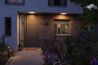 Moderner Hauseingang mit Holzverkleidung und warmweißen LED-Deckenleuchten für Außenbeleuchtung.