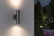 Applique murale extérieure en acier inoxydable avec éclairage haut et bas sur mur blanc dans jardin la nuit