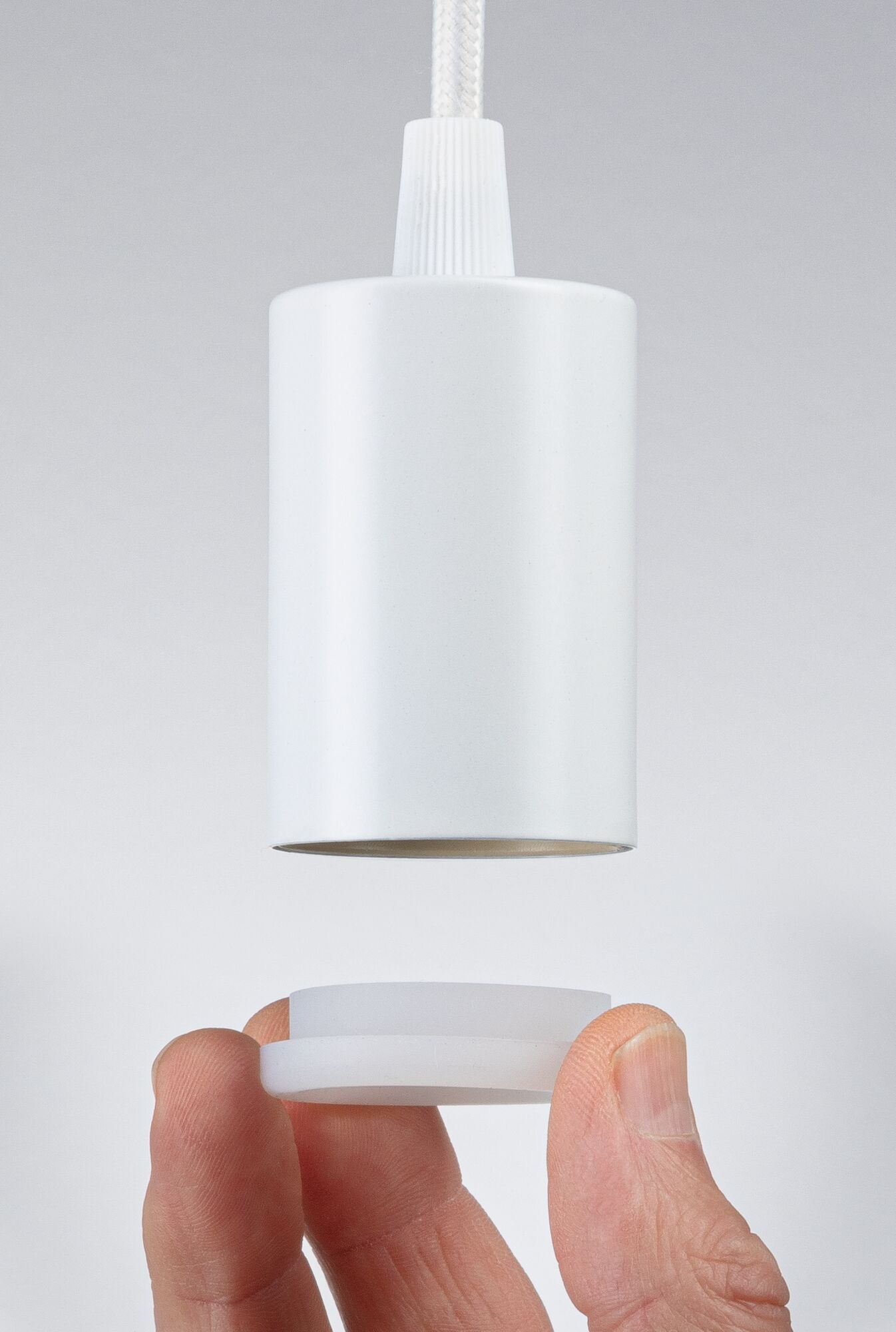 White plastic lamp shade with removable diffuser held by hand, lighting accessory close-up