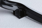 Black plastic mounting bracket with screw hole on white surface for LED lighting fixture.