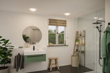 Modern bathroom with round mirror, green sink cabinet and LED ceiling lights for bright lighting