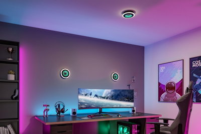 Modern gaming room with round black and green LED wall lights, ultrawide monitor, and RGB lighting setup