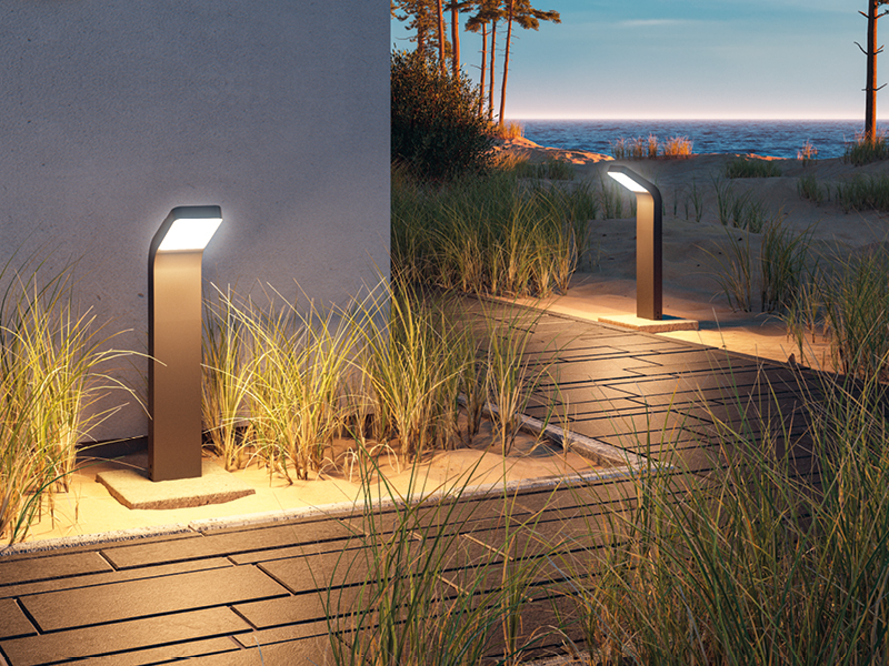 Lanterne LED anthracite en métal moderne sur chemin de plage sableux avec vue sur mer au crépuscule