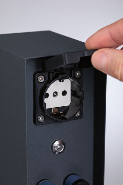 Black socket with protective cover on grey metal housing for secure outdoor power connection