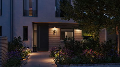 Beleuchteter Hauseingang mit moderner Außenwandleuchte und Gartenwegbeleuchtung in warmweißem Licht