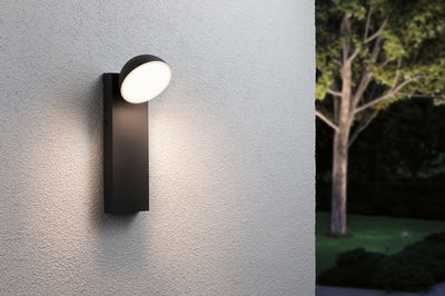 Modern black aluminum wall light with round opal diffuser and warm white LED for outdoor lighting.