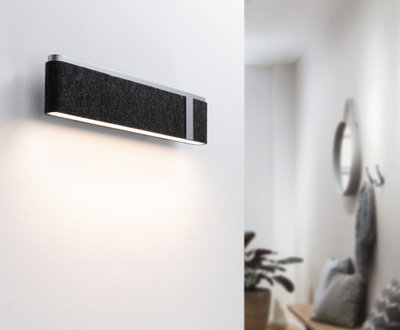 Modern wall light with black felt cover and aluminum frame illuminating white hallway stylishly.