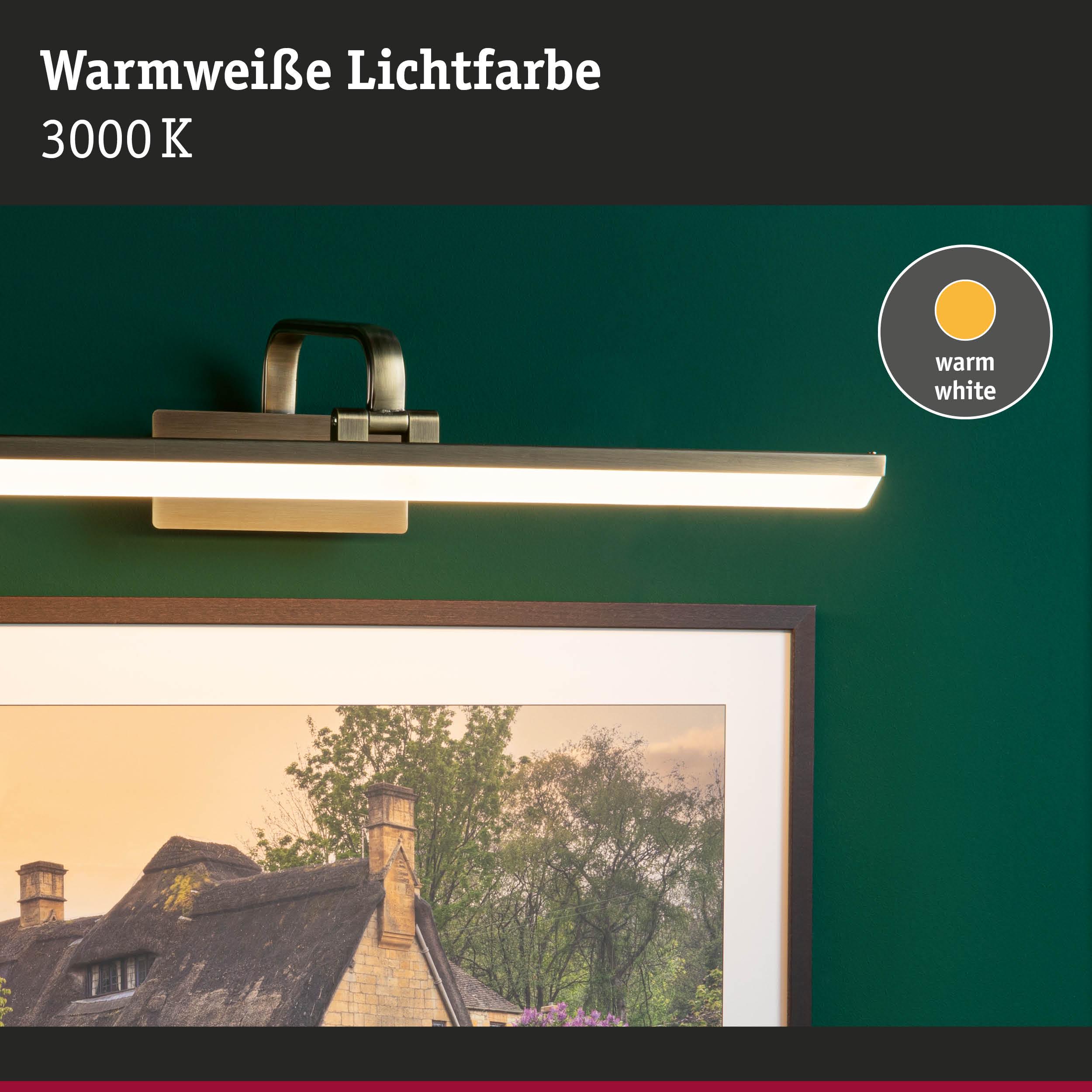 Wandlampe mit warmweißer LED-Beleuchtung 3000K über einem Bildrahmen an grüner Wand