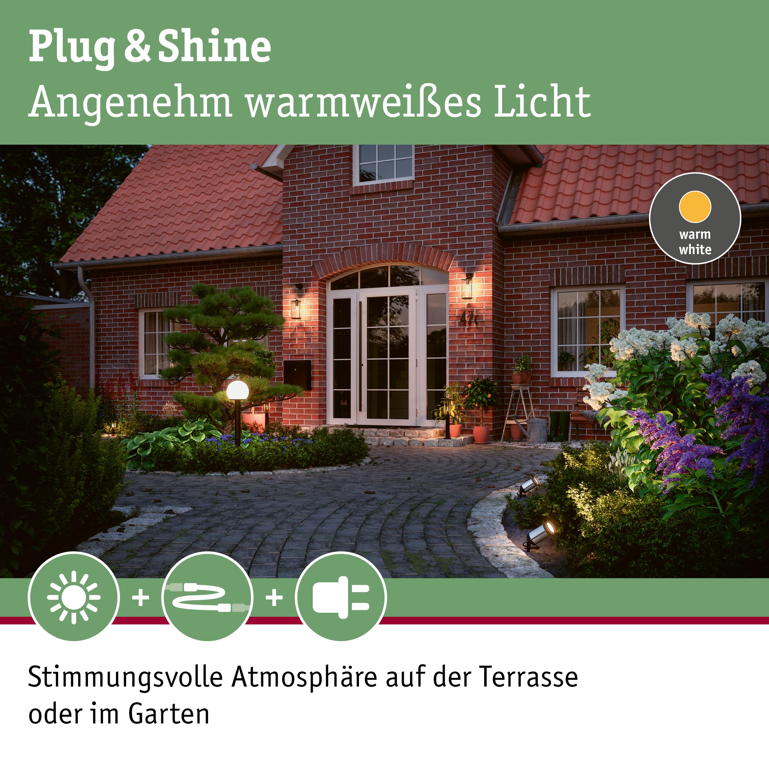 Gemütliche Außenbeleuchtung mit warmweißem Licht an Terrasse und Garten vor rotem Backsteinhaus