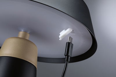 Nahaufnahme eines schwarzen USB-C-Kabels, das in eine graue Lampenfassung mit goldfarbenem Metallteil eingesteckt wird