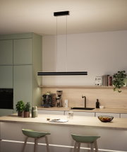 Modern kitchen with black LED pendant light above light wood countertop and green chairs