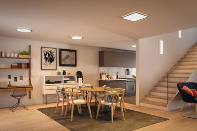 Modernes Esszimmer mit Holzstühlen, Tisch und LED-Deckenleuchten in warmweißem Licht