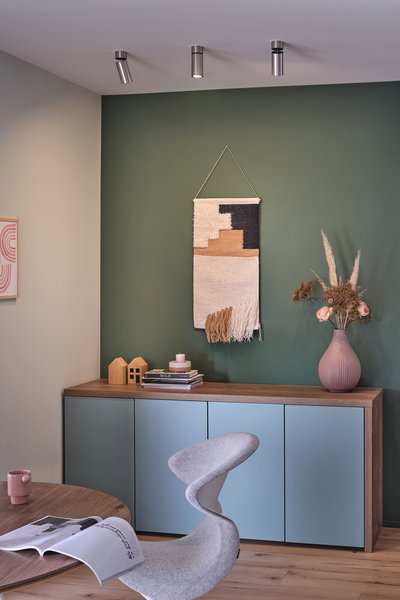 Moderne woonkamer met blauwe houten kast, groene wanddecoratie en zilveren plafondspots voor sfeerverlichting