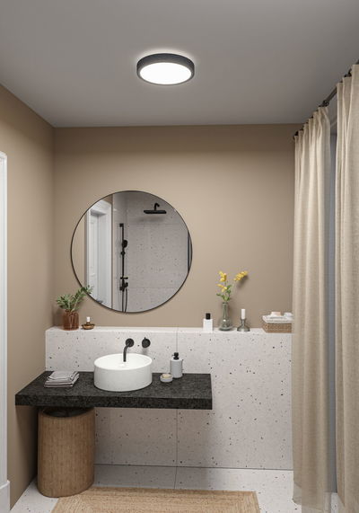 Plafonnier rond avec bord en tissu noir dans salle de bain moderne avec lavabo et miroir.