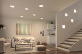 Modern living room with white recessed ceiling lights and square wall lamps on staircase