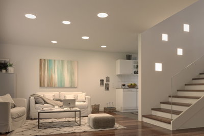 Modern living room with white recessed ceiling lights and square wall lamps on staircase