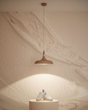 Brązowa metalowa lampa wisząca z ciepłym białym światłem nad kremowym podium z białymi trampkami