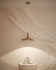 Brązowa metalowa lampa wisząca z ciepłym białym światłem nad kremowym podium z białymi trampkami