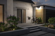 Moderne Hauseingang mit grauer Tür, Fahrrad und Außenwandleuchte mit warmweißem LED-Licht.