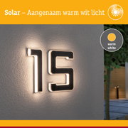 Zonne-energie huisnummer met warm wit LED-licht op grijze muur, moderne buitenverlichting