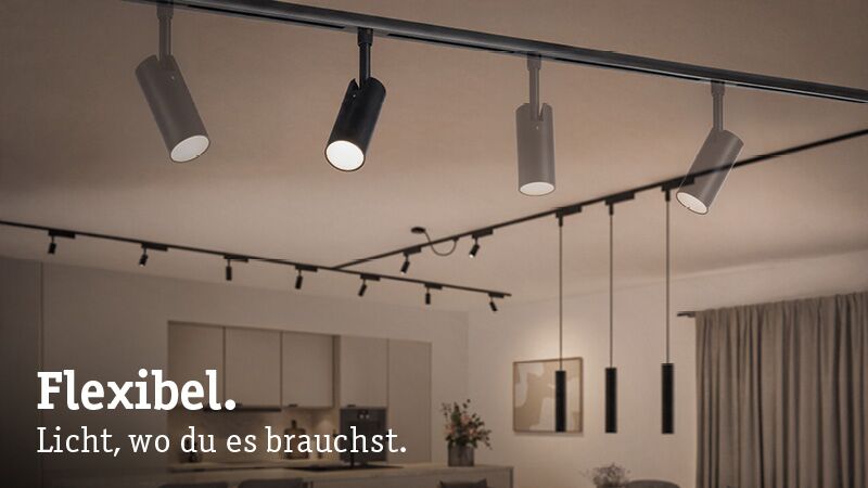 Moderne flexible Deckenstrahler in Schwarz und Weiß in Wohnzimmer mit offener Küche und warmem Licht