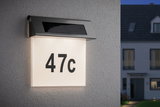 Illuminated house number 47c with solar-powered stainless steel light fixture on white wall