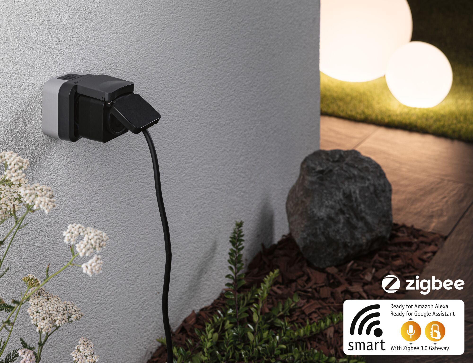 Black smart outdoor socket with flap cover on grey wall, compatible with Zigbee 3.0 gateway and voice assistants.