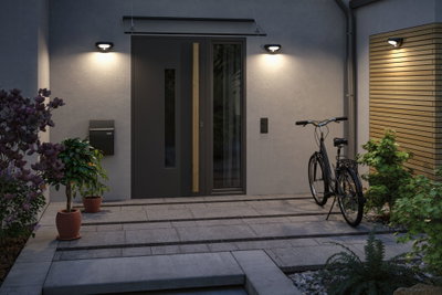 Modern outdoor lighting with black wall lamps at entrance featuring grey door and bicycle.