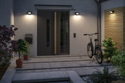 Modern outdoor lighting with black wall lamps at entrance featuring grey door and bicycle.
