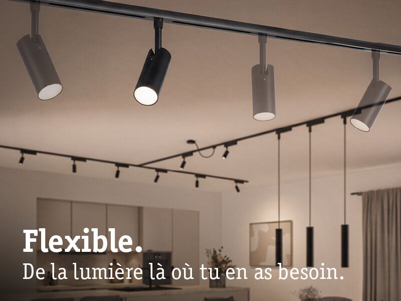 Spots LED flexibles noirs URail au plafond dans un espace de vie moderne avec cuisine ouverte.