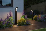 Modern black metal LED outdoor lights illuminate garden path with colorful flowers and wooden privacy fence