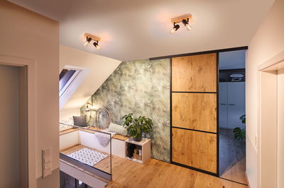 Moderne zolderkamer met houten vloer, groen bladbehang en houten schuifdeur met zwart frame