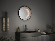 Miroir mural rond de salle de bain avec éclairage LED intégré noir, design moderne avec lavabo et robinet.